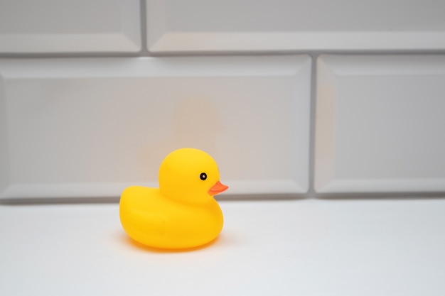 Yellow bath toy duck on a white brick wall in the bathroom.