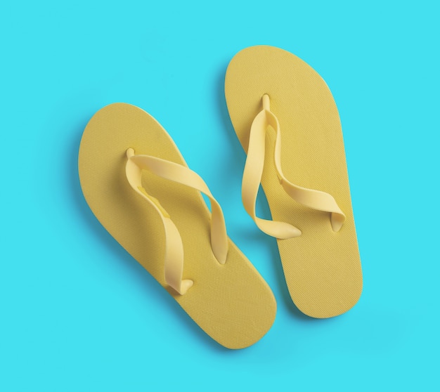 Yellow beach slippers on blue surface. summer concept