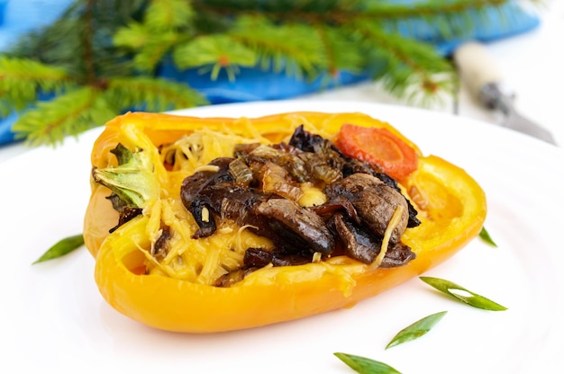 사진 흰색 배경에 접시에 버섯 야채와 치즈로 채워진 노란 피망