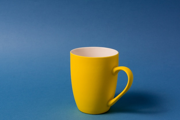 Yellow big mug isolated on blue background.