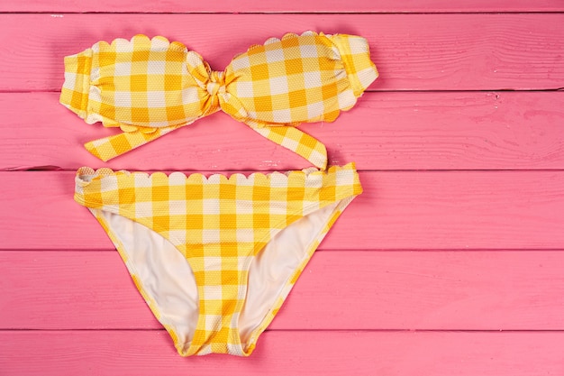 Yellow bikini on bright pink wooden