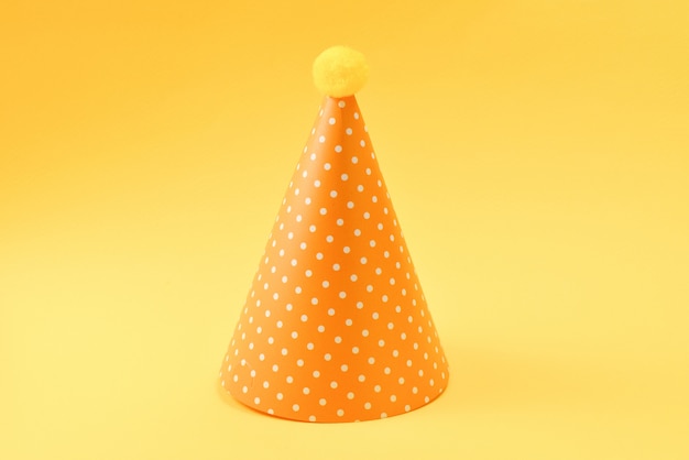 Yellow birthday cap on a yellow background. Copy space.