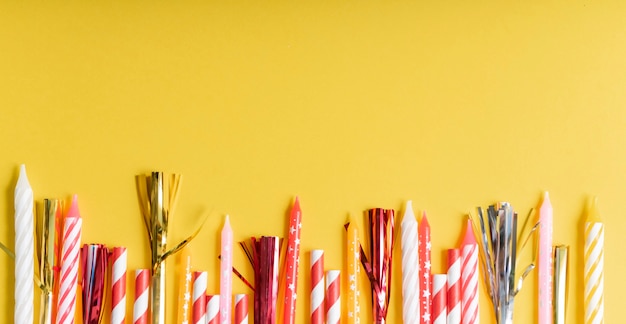 Yellow birthday flatlay. colored paper tubes with wax candles. 