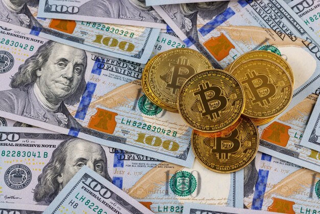 Yellow bitcoin coins scattered over us dollar paper banknotes