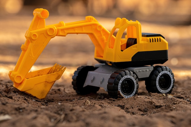 Yellow and black color toy excavator miniature on the ground with selective focus