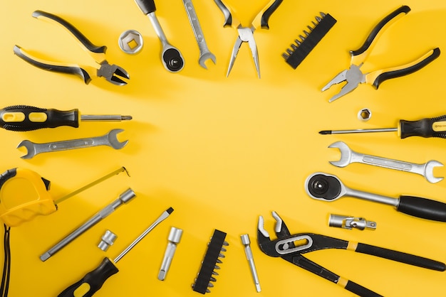 Yellow and black handy tools (pilers and screwdriver) isolated on yellow background