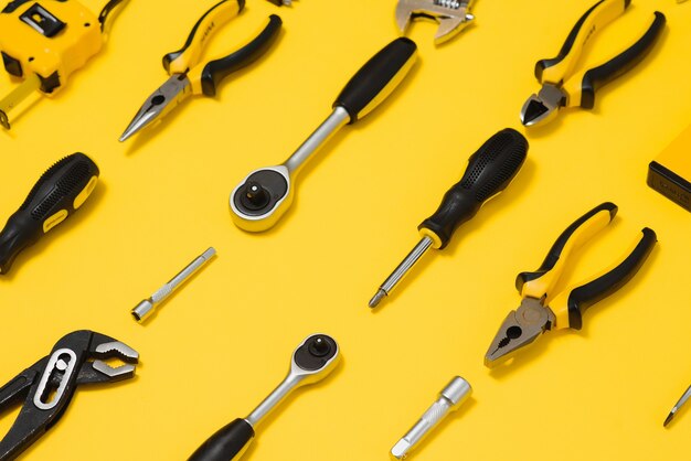 Yellow and black handy tools (pilers and screwdriver) isolated on yellow background