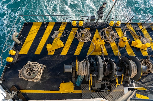 Yellow and black painted ferry deck boat along with the a thick mooring rope and blue sea water wave Thailand Close up