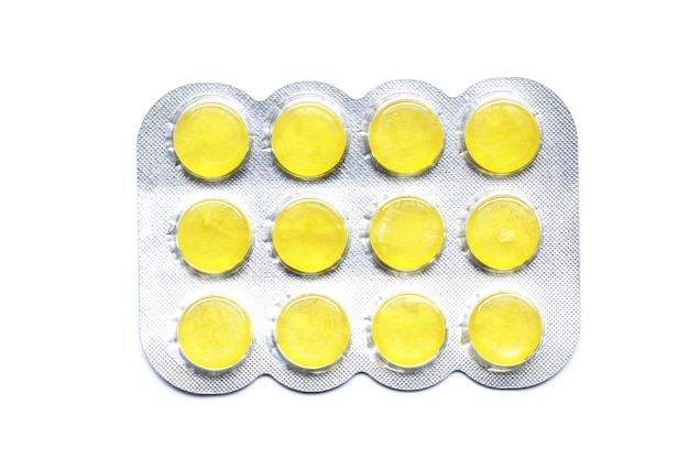 Yellow Blisters with color cough drops isolated on a white background.