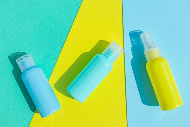 Yellow and blue cosmetic bottles on the same colored space. Stylish concept of organic essences, beauty and health products. Copy space, minimalism, flat lay.