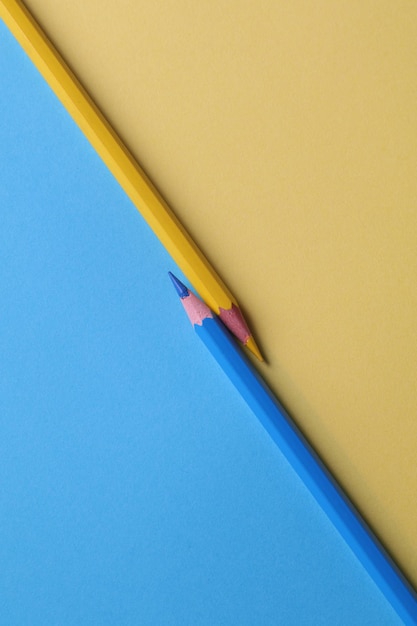 A yellow and blue pencil is next to a blue one that has a yellow one.