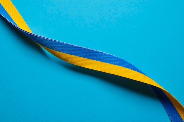 Yellow and blue Ukrainian national flag colors fabric ribbon on blue paper background Ukraine