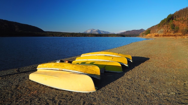 Желтые лодки, сделанные из старого дерева для рыбаков, отправляются на рыбалку к красивому озеру и ясному голубому небу в районе Фудзи Токио, Япония.