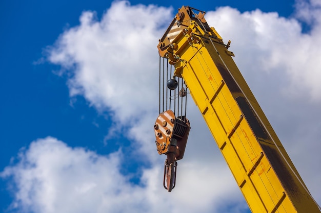 Photo yellow boom of a loading crane against a blue sky with clouds