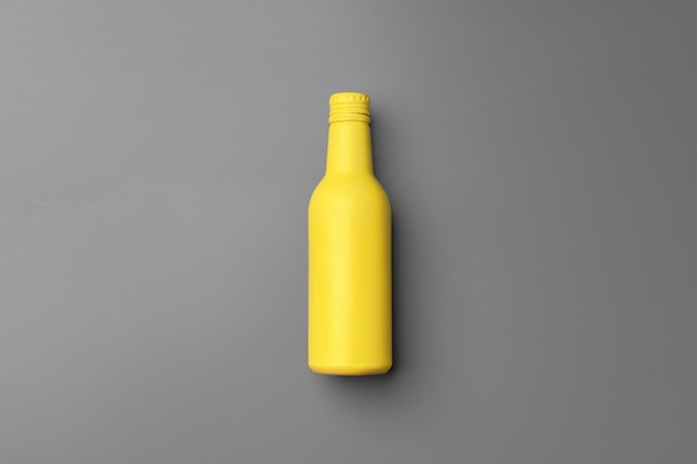 Yellow bottle on gray background flat lay