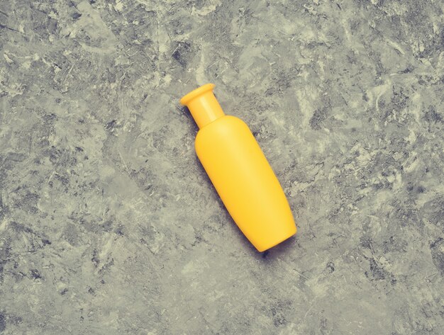 Yellow bottle of shampoo on a gray concrete table