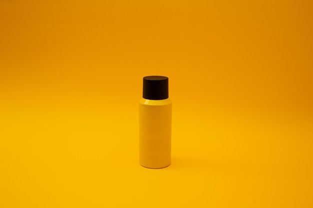Желтая бутылка стоит на желтом фоне