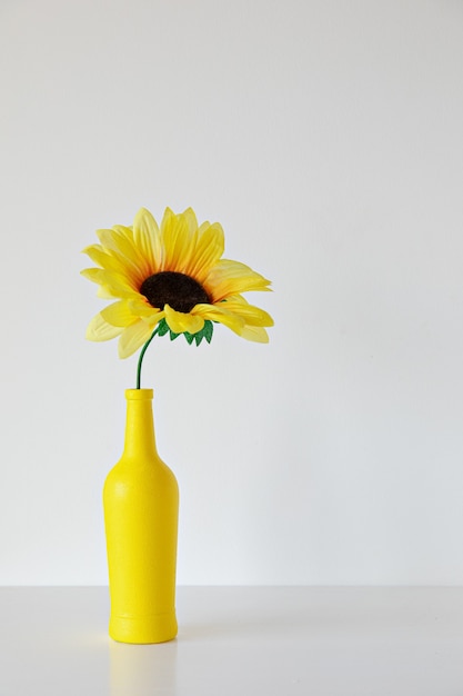 Yellow bottle with sunflower on white background