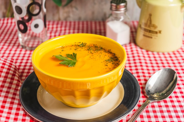 Yellow bowl with cream of squash and carrots soup Horizontal framing