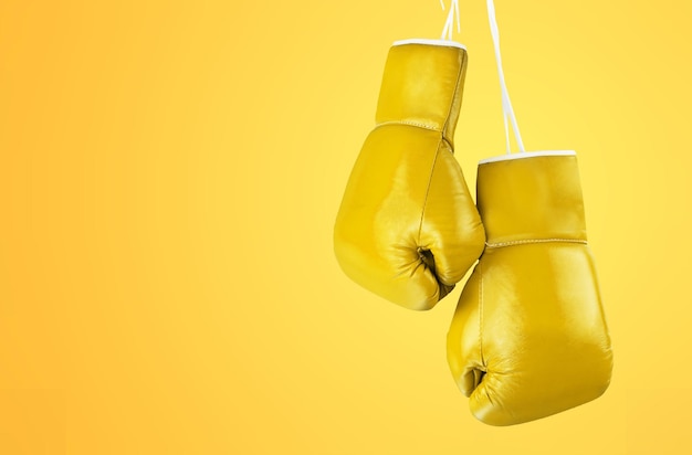 Yellow boxing glove on yellow colored background.