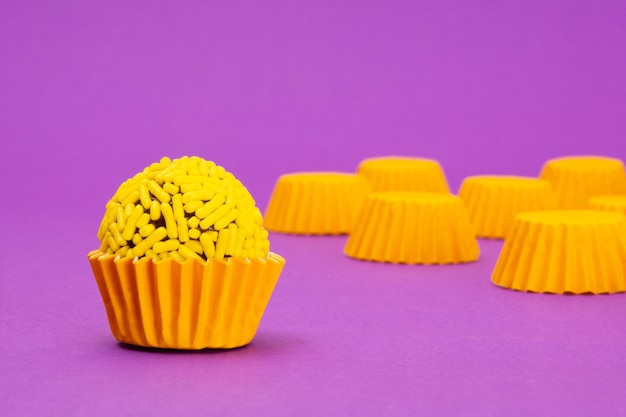 Foto brigadeiro giallo, dolce tradizionale brasiliano, su fondo viola, confezione gialla