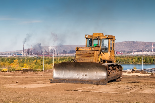 Yellow bulldozer against the backdrop of an industrial landscape