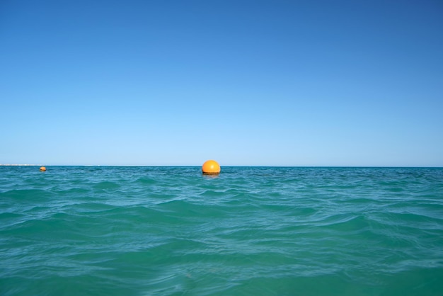 Yellow buoy floating on sea surface as marker for swimming restriction in deep water at tropical resort Human life safety concept