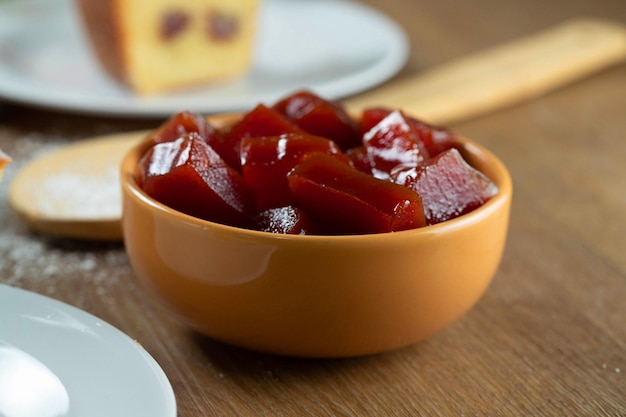 Lattina gialla con marmellata di guava tagliata a cubetti con guaiave sullo sfondo sul tavolo di legno