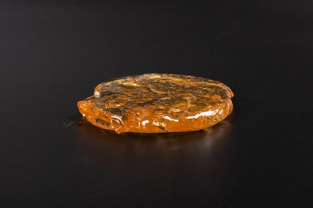 Yellow cannabis wax on black background marijuana golden dab