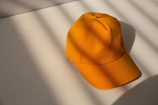 A yellow cap sits on a white table with a shadow of the sun.