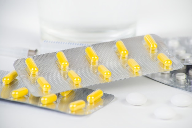 Yellow capsules in a blister lie on a green background.