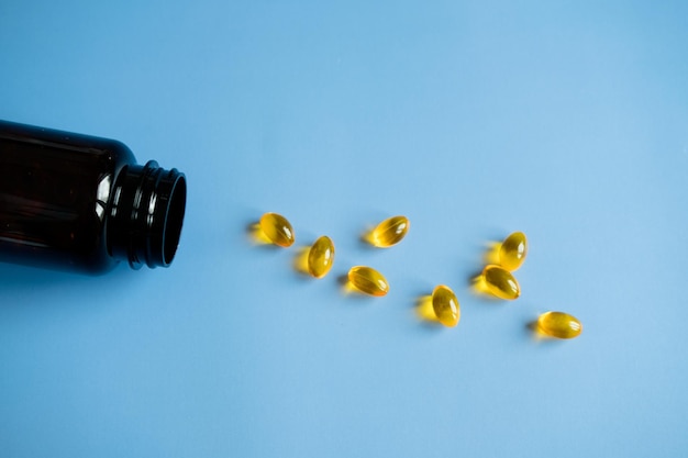 Yellow capsules of fish oil on a blue background Useful vitamins Taking care of your health