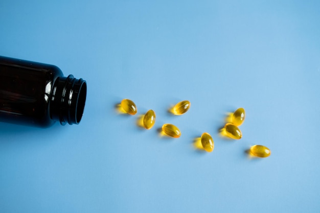 Фото Желтые капсулы рыбьего жира на синем фоне полезные витамины забота о здоровье
