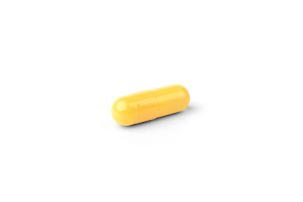 Желтые капсулы или таблетки, изолированные на белом фоне.