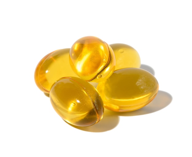 Photo yellow capsules with fish oil on a white background close up