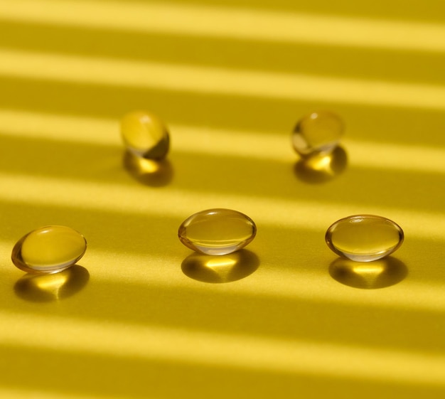 Yellow capsules with fish oil on a yellow background close up