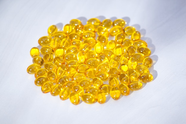 Yellow capsules with vitamin D, fish oil omega 3 with sunlight. Healthy and medical concept.