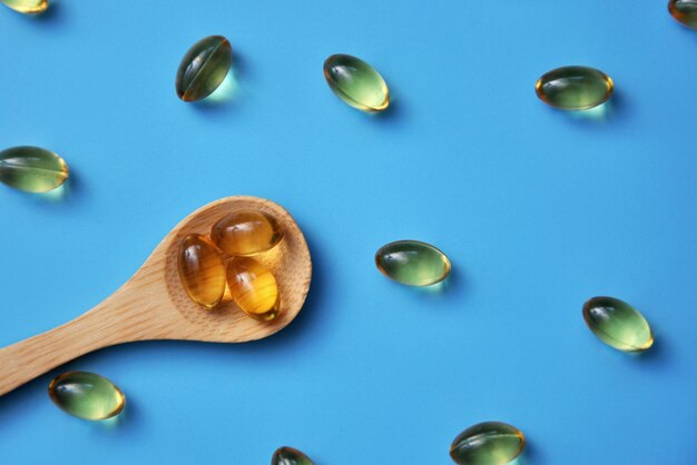 Yellow capsules on a wooden spoon and next to it