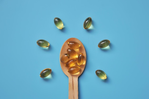 Photo yellow capsules on a wooden spoon vitamin d