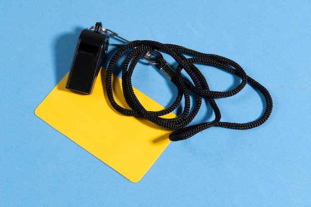 Yellow card and referee whistle with space for text in a blue background