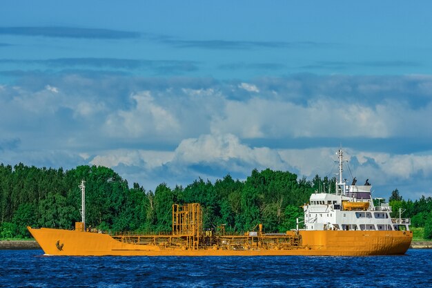 Yellow cargo tanker ship moving at the clear summer day