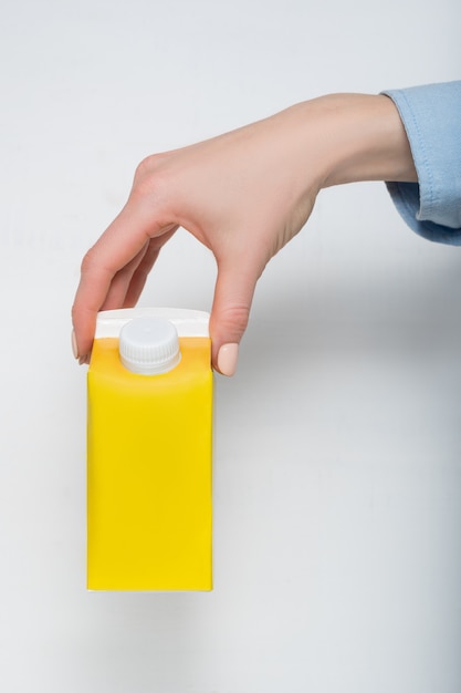 Yellow carton box with a cap in a female hand.