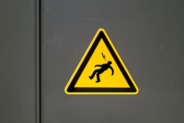Yellow caution sign on a metal door warning about Danger of death