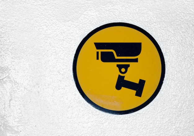 Yellow CCTV sign painted on a wall