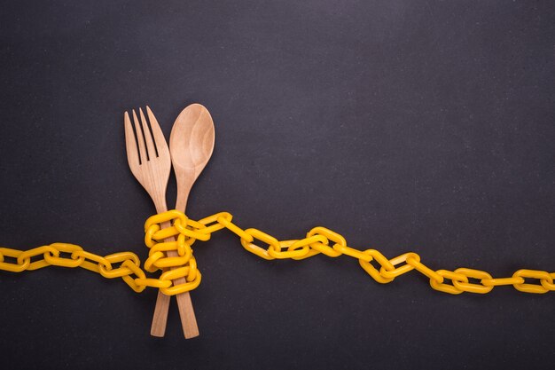 Yellow chain locked around the wooden spoon and fork