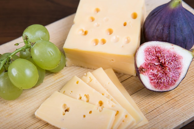 Yellow cheese and fresh figs on the wooden cutting board