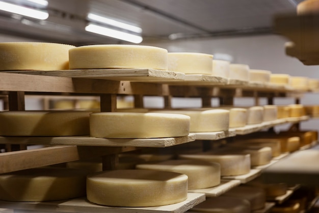 Yellow cheese heads lie on wooden shelves. Cooking process. Close-up. Soft focus.