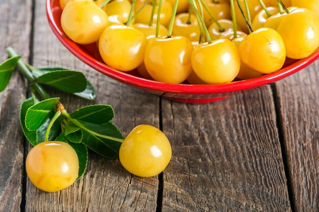 Yellow cherry in bowl on a wooden background