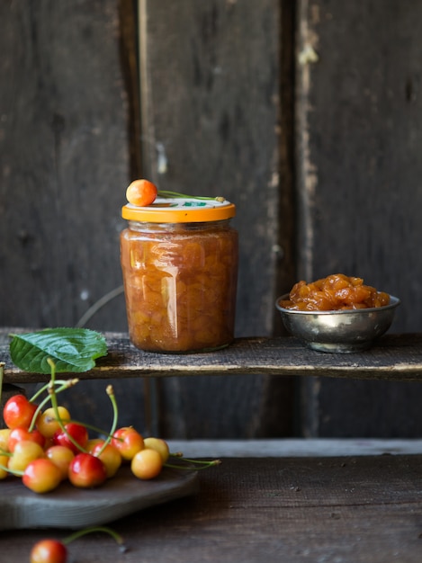 Yellow cherry jam with a rustic tablecloth. jam cherry with\
fresh berry. sweet food.