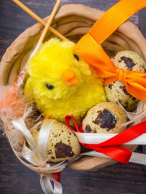 Yellow chick in clay bowl with easter eggs